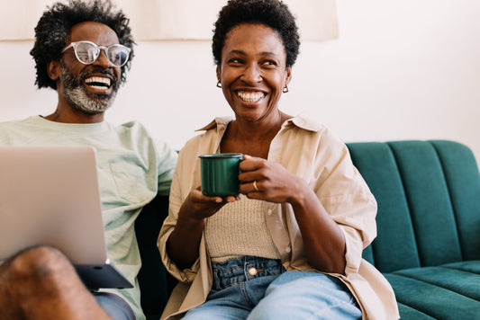 a menopausal woman and her partner laughing on the couch