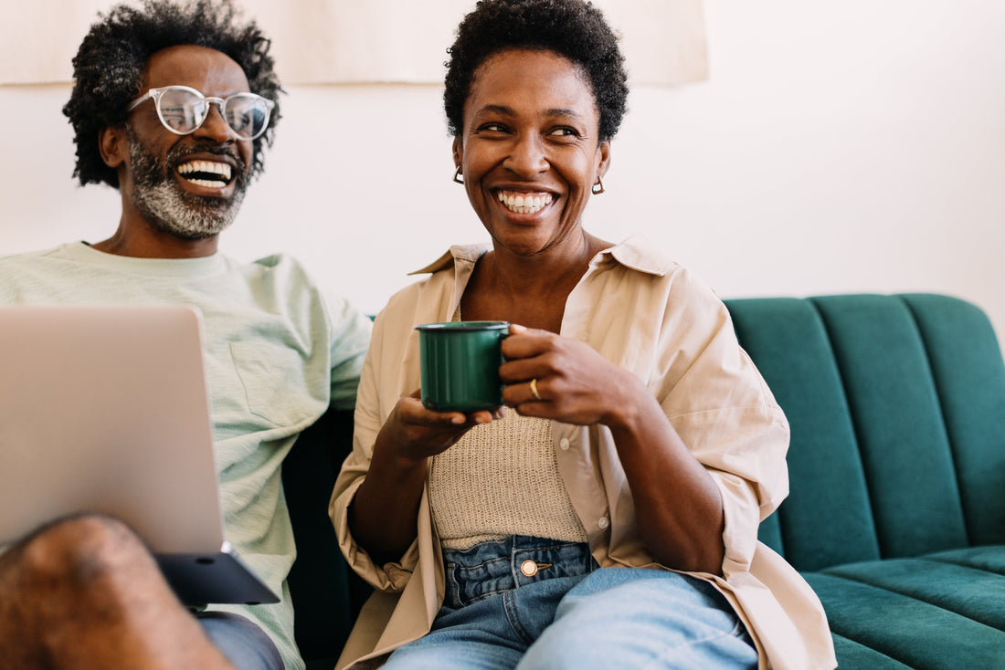 a menopausal woman and her partner laughing on the couch