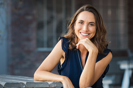 a perimenopausal woman leaning on a table and smiling