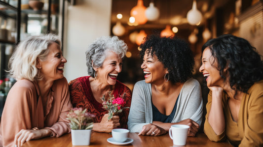 four older women sat at a table and laughing together