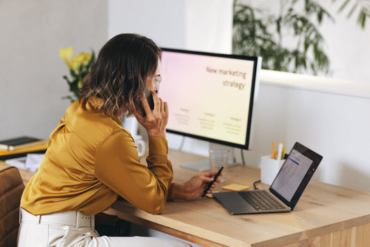 a woman working at her desk with a laptop and monitor