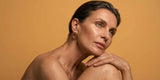 A nude woman contemplating against a golden orange background