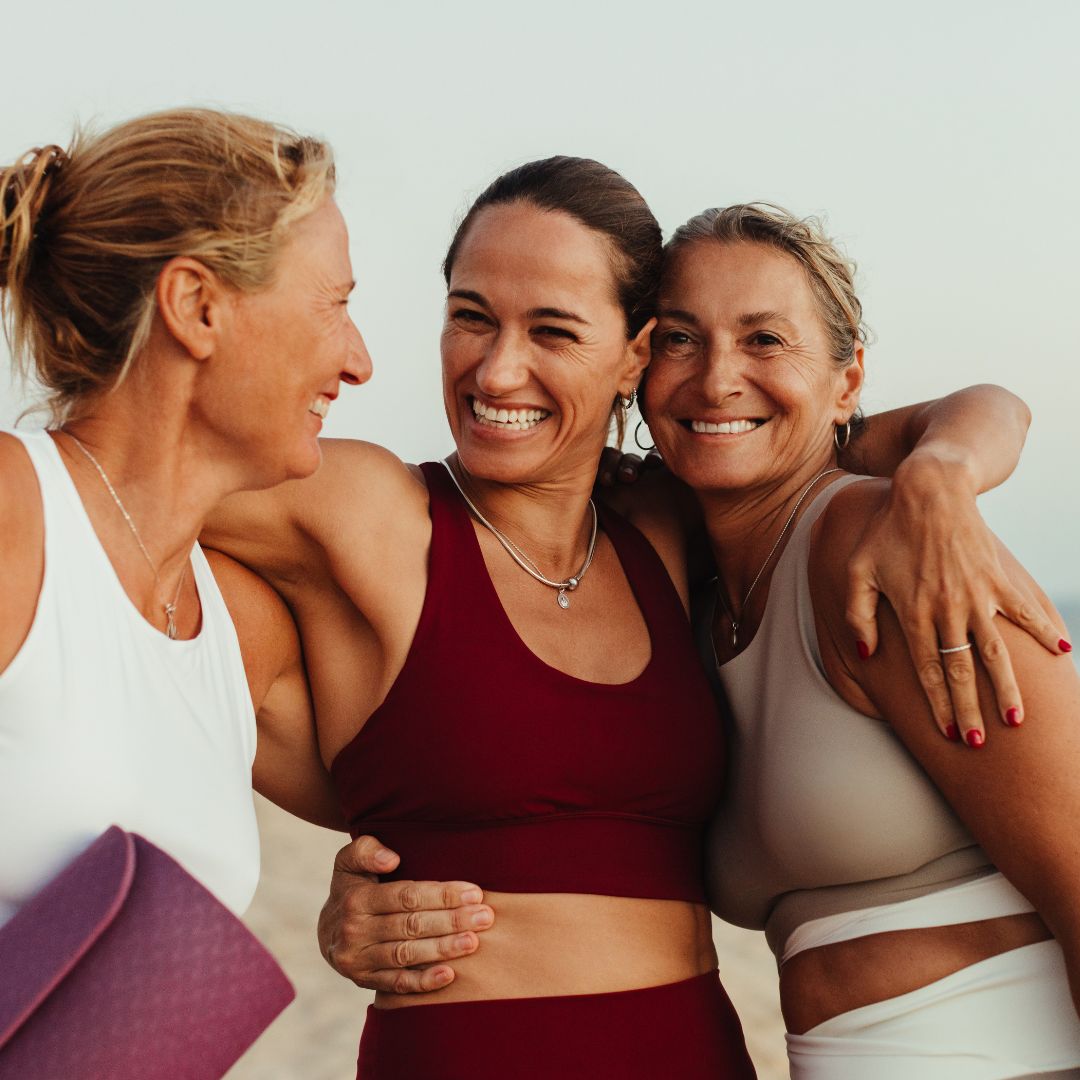 three women hugging and laughing wearing activewear