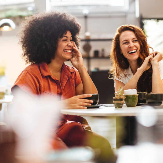 two menopausal women laughing over a coffee