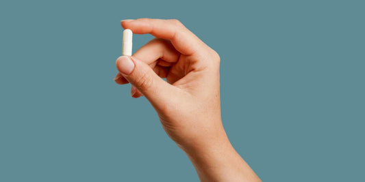 A hand holding a Serelys Meno supplement against a blue background