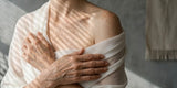 An older woman wearing a sheer top with her shoulder showing