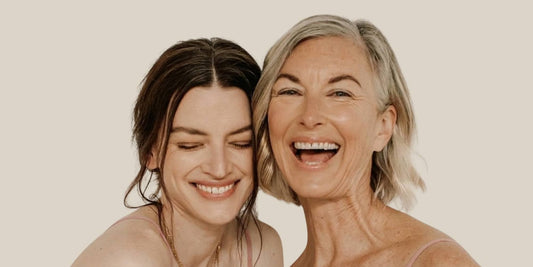 Two women of different ages smiling against a nude background
