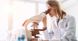 Person in a lab coat using a microscope in a laboratory setting