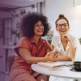 Two women in a workplace setting smiling and laughing into the distance