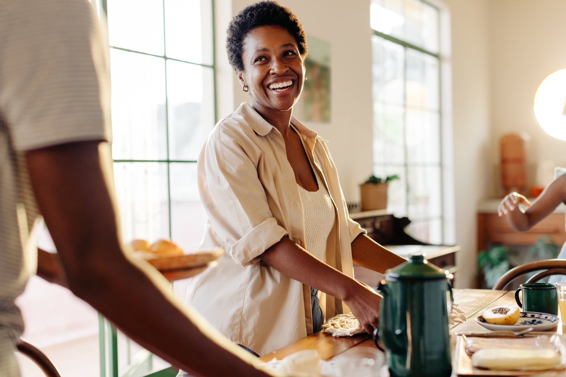 Woman in a kitchen setting with a smile, surrounded by a homey atmosphere.